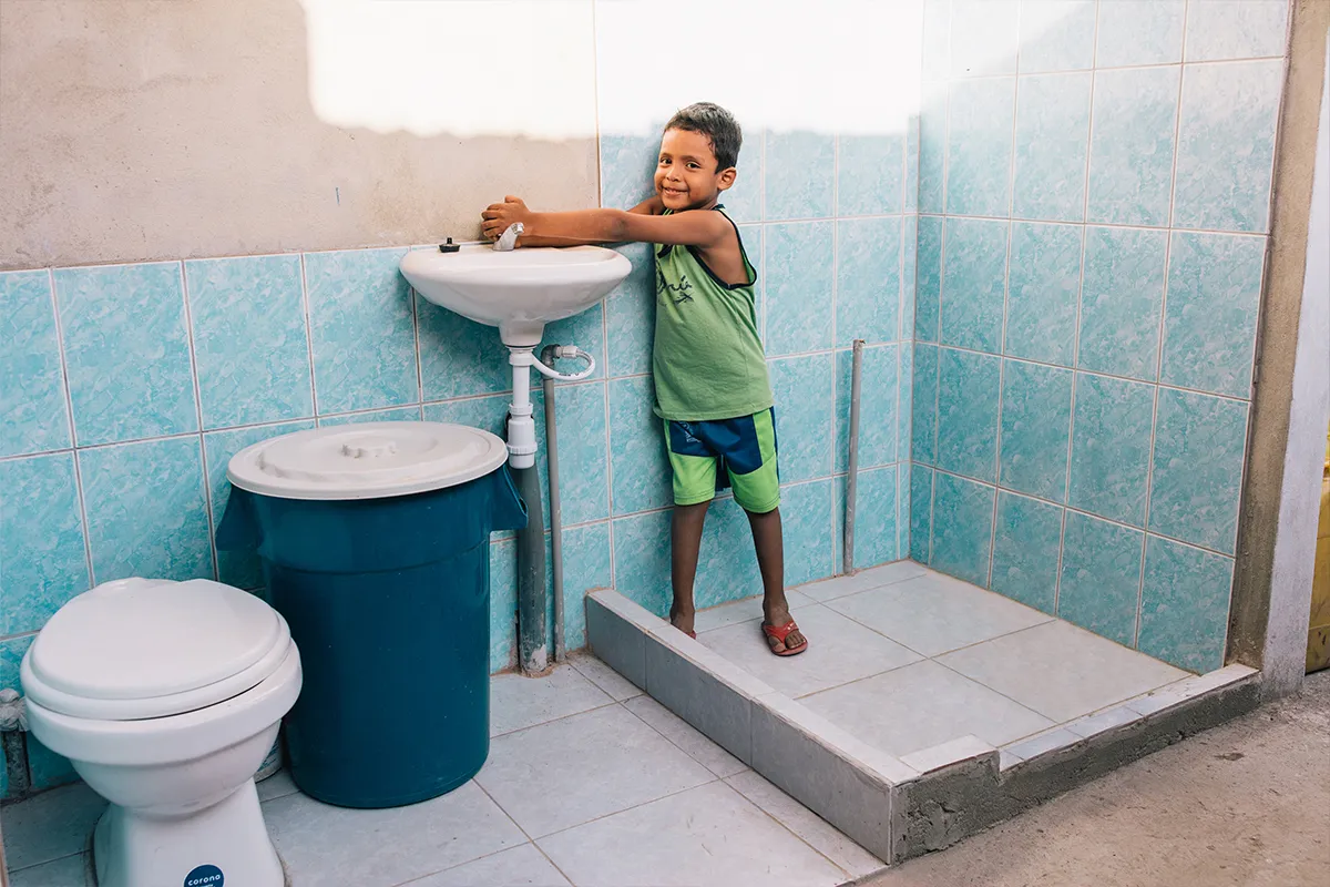 A boy in Peru washes his hands at a bathroom sink.