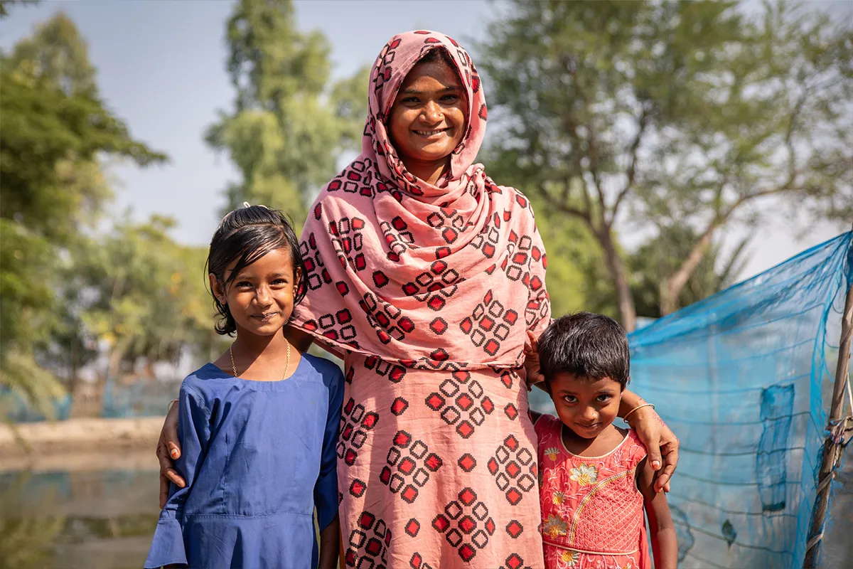 Mother smiling with her arms around her two daughters.