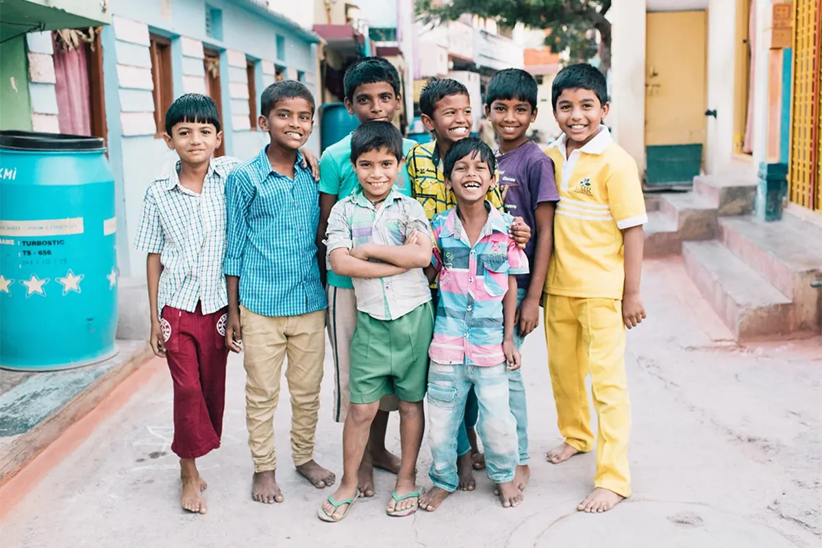 A group of eight smiling boys standing together in their neighborhood