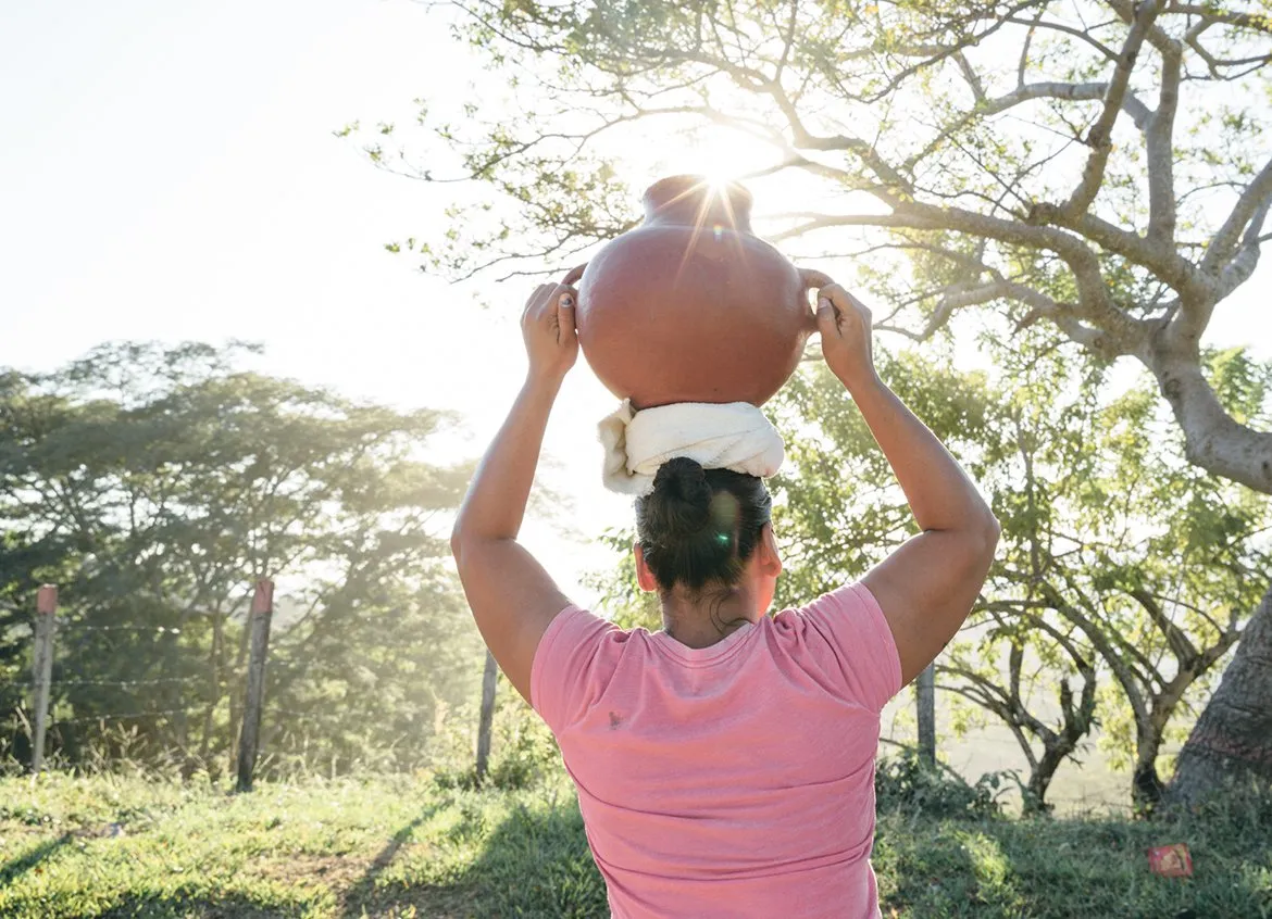 Woman carries a water vessel on her head in Honduras.