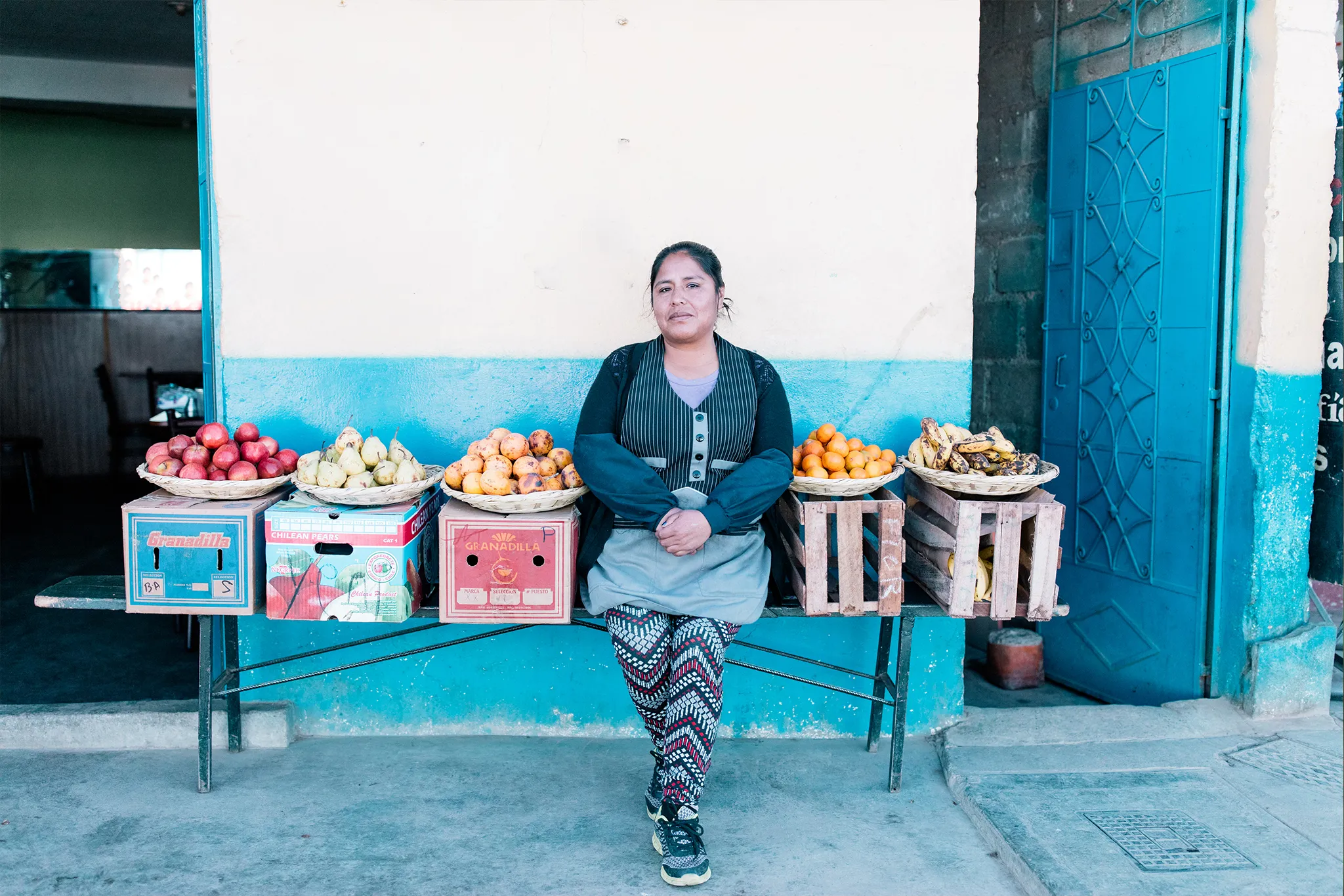 Woman standing in front of her fruit stand.